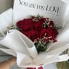 Bouquet of red roses wrapped in white paper with a love card