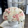 Round bouquet of blush and white roses in a white pedestal vase