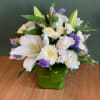 White floral arrangement in a green square vase with purple accents