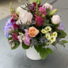 Mixed bouquet of pink, white, and peach flowers in a white vase