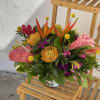 Tropical bouquet with pink, orange, and yellow flowers in a glass vase