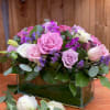 Pink and lavender roses arranged in a glass rectangular vase