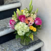 Mixed bouquet of pink roses, lilies, and hydrangea in a glass vase