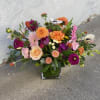 Mixed bouquet of colorful flowers in a square glass vase