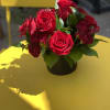 Red roses arranged in a black vase on a yellow table