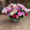 Mixed pink and white roses arranged in a gray vase
