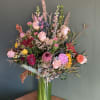 A mix of fresh blooms and dry flowers, in glass vase.