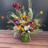 Colorful mixed flower arrangement in a green glass vase