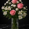 Pink roses and white flowers arranged in a clear glass vase