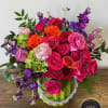 Bright mixed arrangement of pink, red, orange, and purple flowers in a green ceramic vase.