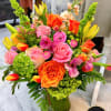 Bright mixed bouquet of pink, orange, and green flowers in a clear glass vase
