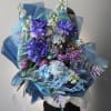 Large bouquet of purple and blue flowers wrapped in blue paper