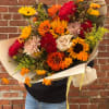 Large bouquet of sunflowers, dahlias, and roses wrapped in cream paper