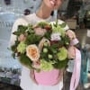 Woman holding a pink box of pastel roses and green carnations