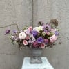 Lavender and pink floral arrangement in a gray urn vase