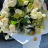 Large bouquet of white and pale green flowers wrapped in white paper