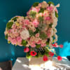 Heart-shaped floral arrangement with pink roses and carnations on a pedestal