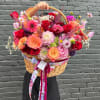 Large wicker basket filled with colorful mixed flowers and ribbon