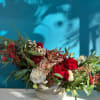 Red and white roses arranged in a low stone vase with berries