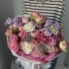 Large bouquet of pink and lavender flowers wrapped in white paper