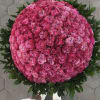 Large round bouquet of pink roses with a dark green leaf border