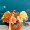 Floral arrangement in a pumpkin with orange, cream, and peach blooms