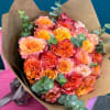 Bouquet of orange and pink roses wrapped in brown paper