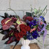 Bold mixed bouquet in a white vase with red, purple, and blue flowers
