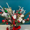 Christmas arrangement with Santa figurine, ornaments, and cotton stems in a plaid container