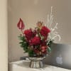 Red rose arrangement in a silver vase with white decorative branches