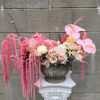 Pink floral arrangement in a stone urn with cascading blooms