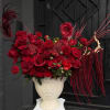 Red floral arrangement in a white pedestal vase