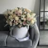 Large pastel flower arrangement in a white hatbox with a ribbon