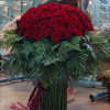 Large bouquet of red roses with dark greenery and ribbon