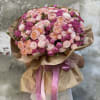 Large bouquet of pink and peach roses wrapped in brown paper with pink ribbons