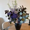 Tall mixed bouquet in a black vase with blue, purple, and white flowers