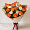 Bouquet of orange roses and white ranunculus wrapped in cream paper