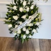 White rose standing spray with a condolence ribbon on an easel
