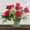 Red roses arranged in a clear glass vase with white filler flowers