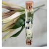 Perfume bottle beside a white flower and green leaves