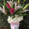 Bright pink roses paired with white lilies and a dense collar of