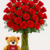 Bouquet of red roses in a clear glass vase with a teddy bear holding a heart