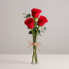 Three red roses in a clear glass vase tied with twine