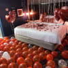 Bedroom decorated with heart balloons and rose petals on the bed
