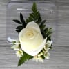 White rose boutonniere with small white blossoms and greenery