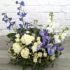 White roses and purple irises arranged around a clear glass cross