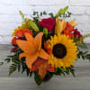 Bouquet of orange lilies, red roses, and a yellow sunflower in a vase