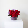 Red roses and lavender flowers in a purple glass vase