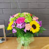 Mixed bouquet with pink roses, sunflowers, and purple flowers in a glass vase