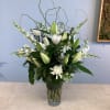 White lilies and chrysanthemums arranged in a clear glass vase
